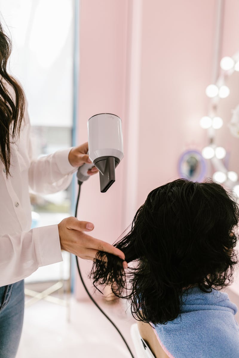 Stylist blow-drying client's hair in a sleek, chic salon setting