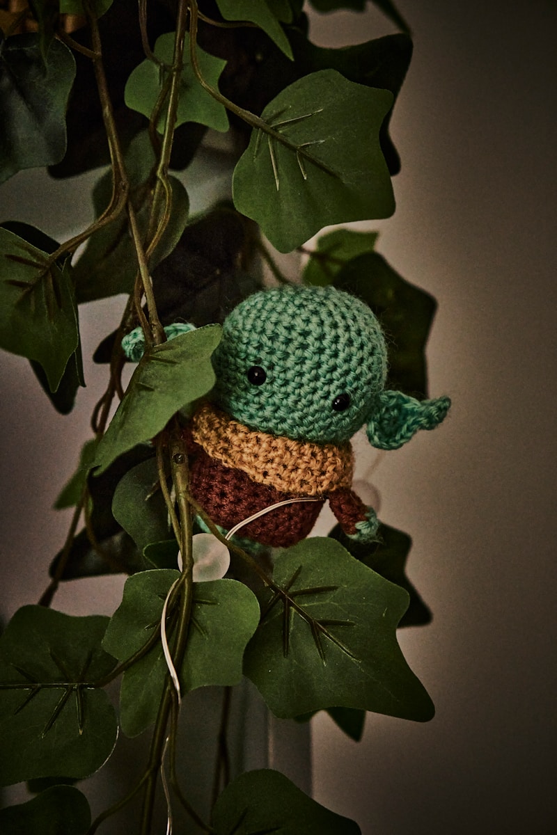 a crocheted yoda is hanging from a plant